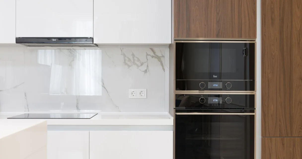 Cozinha branca com fornos embutidos pretos, ilustrando o micro-ondas e o Wi-Fi